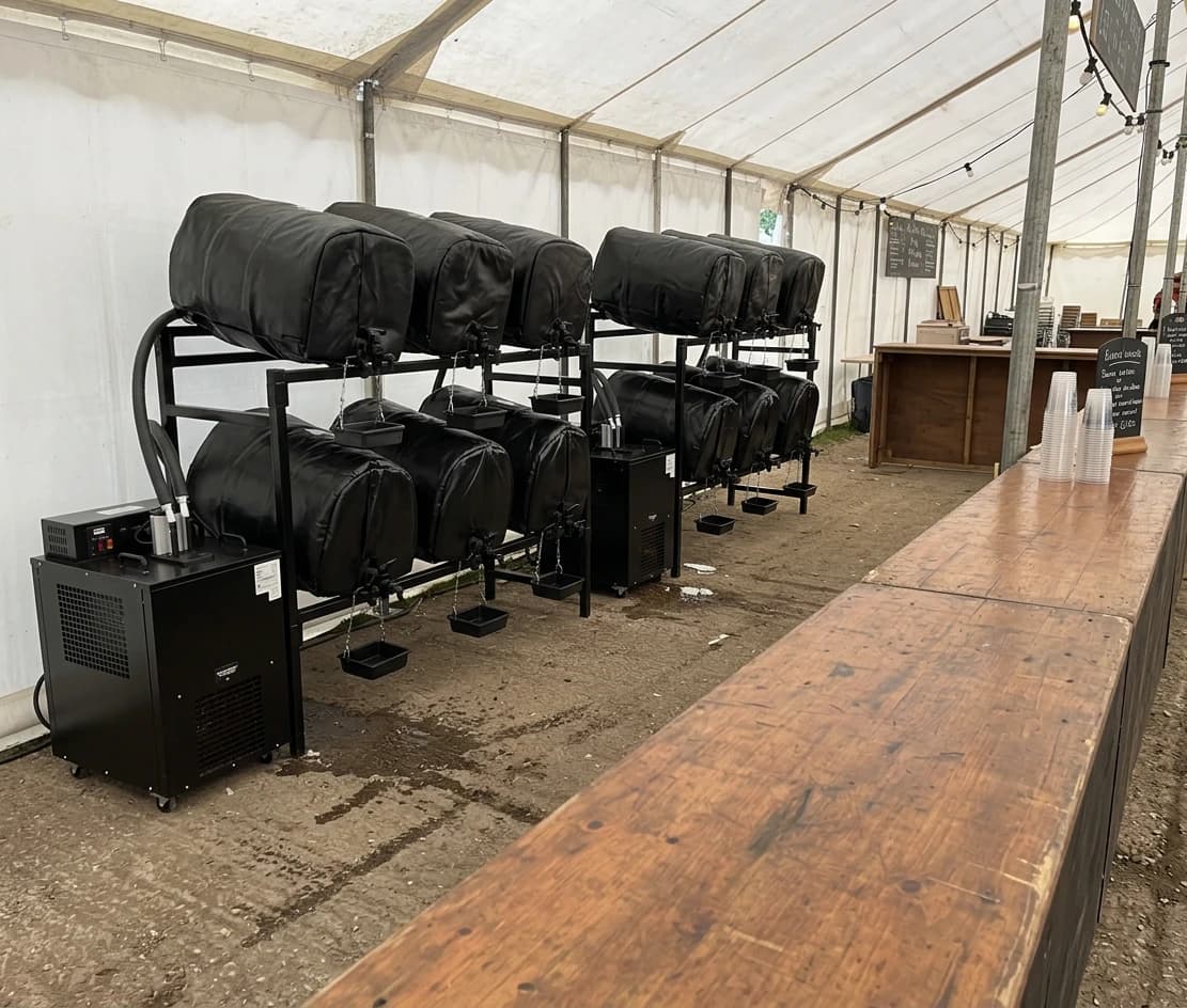 Village Festival Kit set up in a marquee - twelve casks racked with piped cooling jackets and taps across two ranks, ready to pour